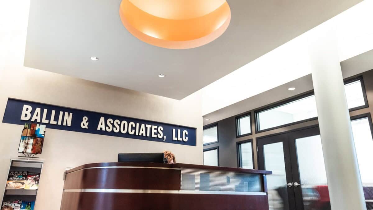 Reception area of Ballin & Associates, LLC featuring a modern desk, magazine rack, and signage.