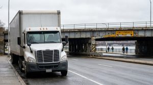 large commercial truck approaching overpass with Low Clearance warning sign